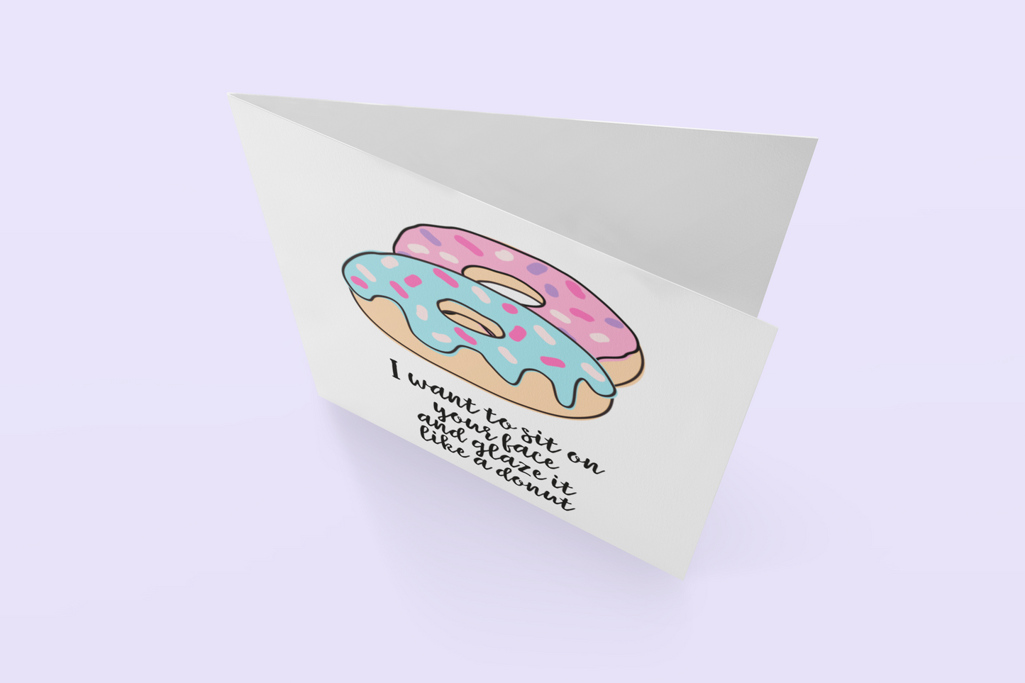 White vertical greetings card featuring a colourful donut design. To the bottom it reads 'i want to sit on your face & glaze it like a donut'. Printed in black ink.