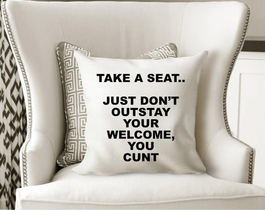 White cushion cover with the funny quote, take a seat, just don't out stay your welcome, you cunt. Cover only, Zip fastener and printed one side