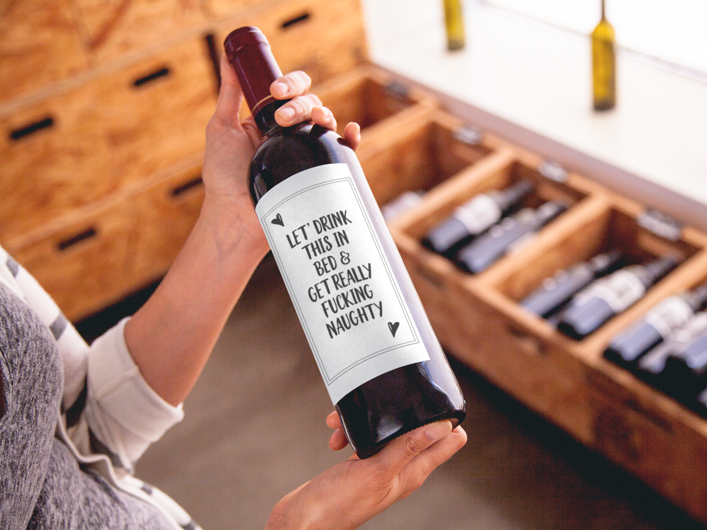 A bottle of wine featuring a custom label which reads 'let's drink this in bed & get really fucking naughty'. Printed in black ink.