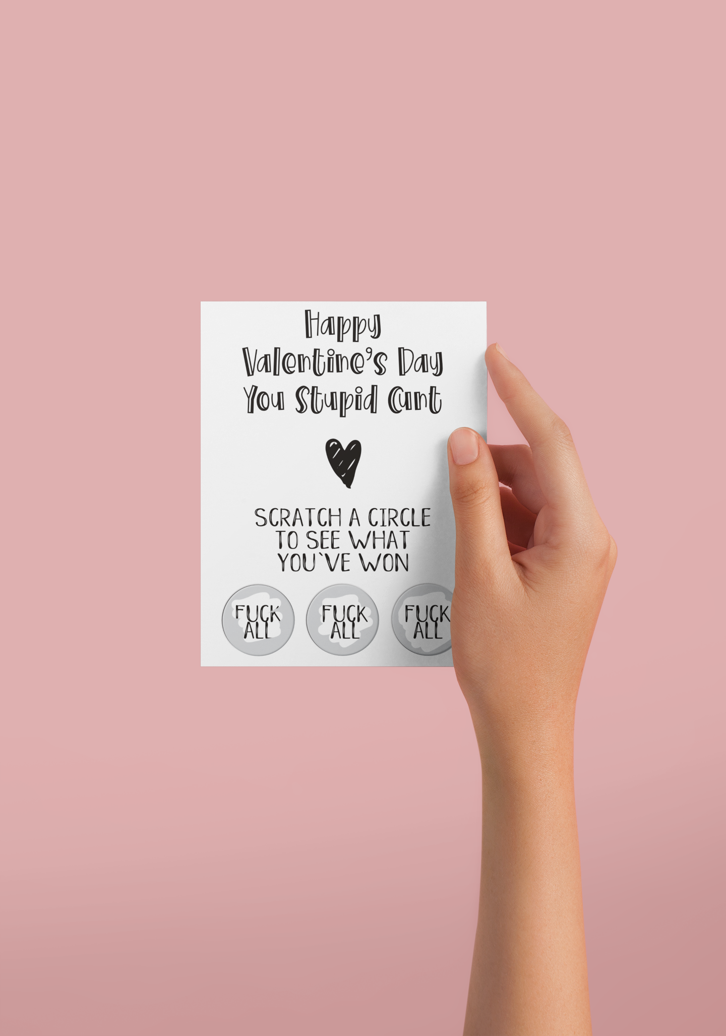 White vertical greetings card saying 'happy valentine's day you stupid c*nt' with a heart underneath. Then below is 'scratch a circle to win a prize'. To the bottom are 3 scratch stickers revealing the prizes. All printed in black ink.
