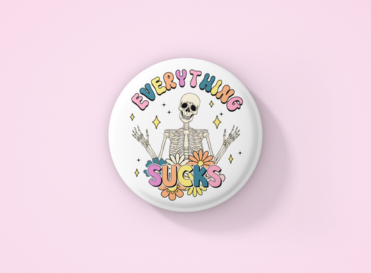 White Badge with a skeleton design and the quote Everything Sucks