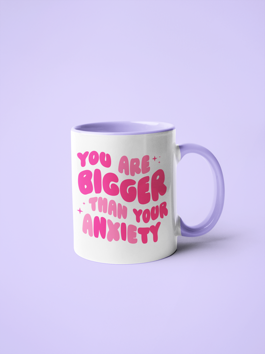 11oz white mug with purple handle, bold pink text 'YOU ARE BIGGER THAN YOUR ANXIETY' design.