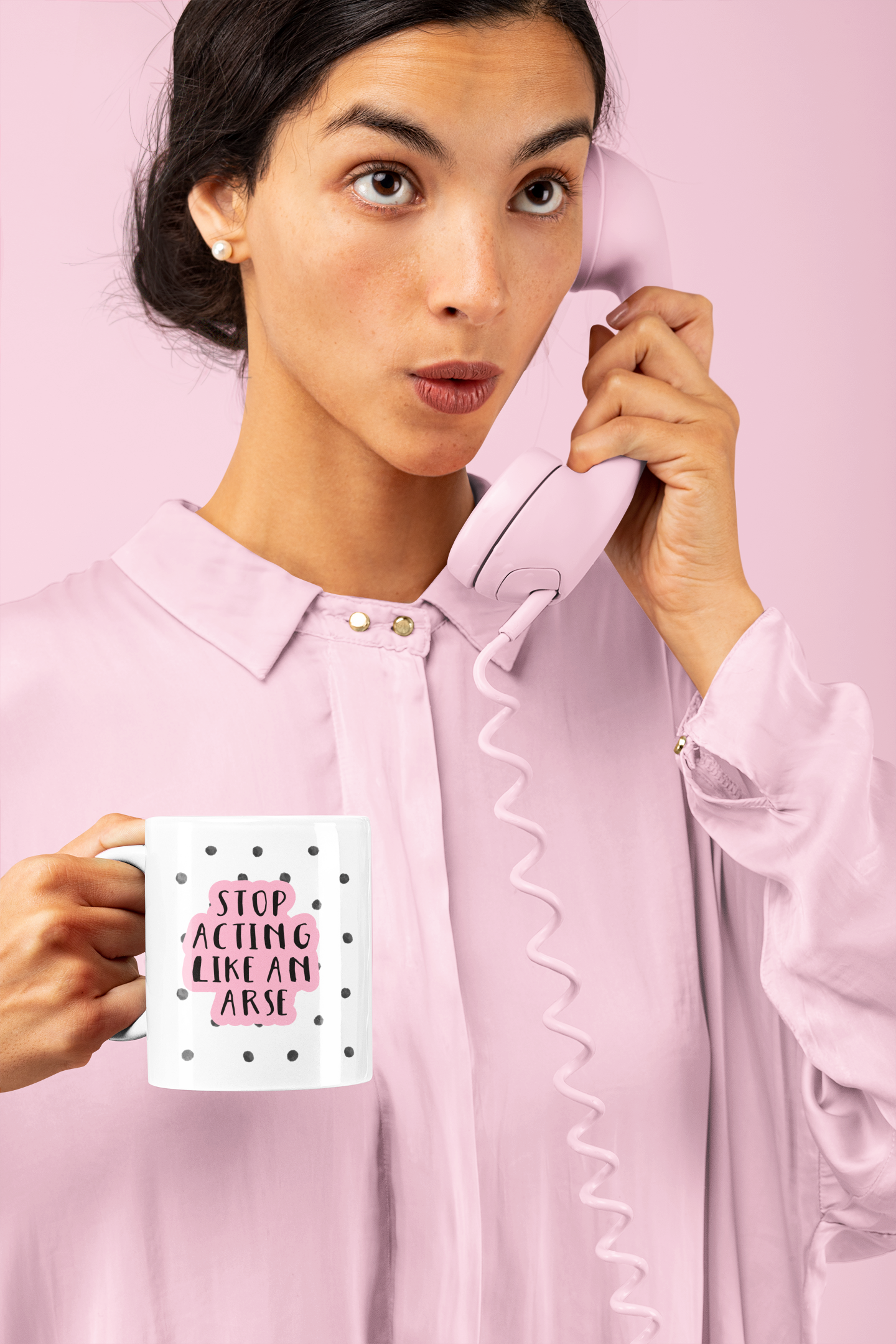 White ceramic mug with a black water-coloured spotty background & the quote 'stop acting like an arse' situated over the top. The wording is printed in black with a baby pink outline.