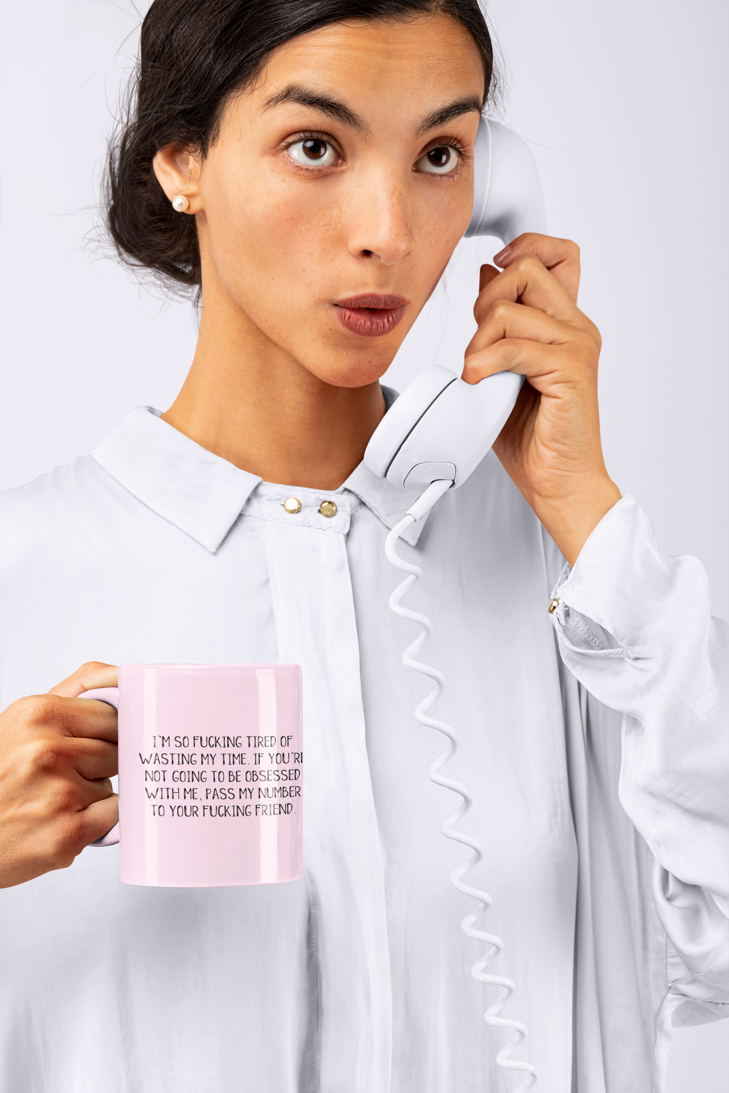 Woman holding a white ceramic mug featuring the funny quote 'i'm so fucking tired of wasting my time. If you're not going to be obsessed with me, pass my number to your friend'. Printed in black ink.