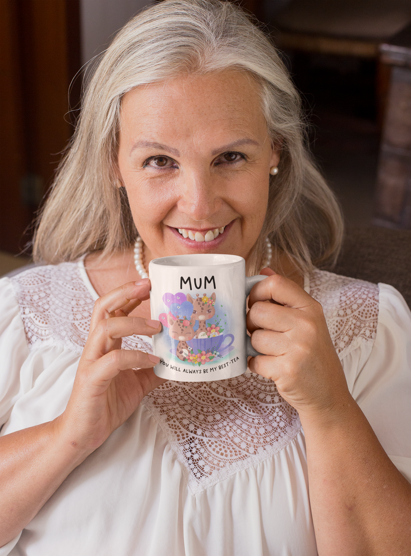 white mug with a pink handle featuring cute pastel colour giraffes sitting in a teacup with the word 'mum' at the top and to the bottom is reads 'you will always be my best-tea'.