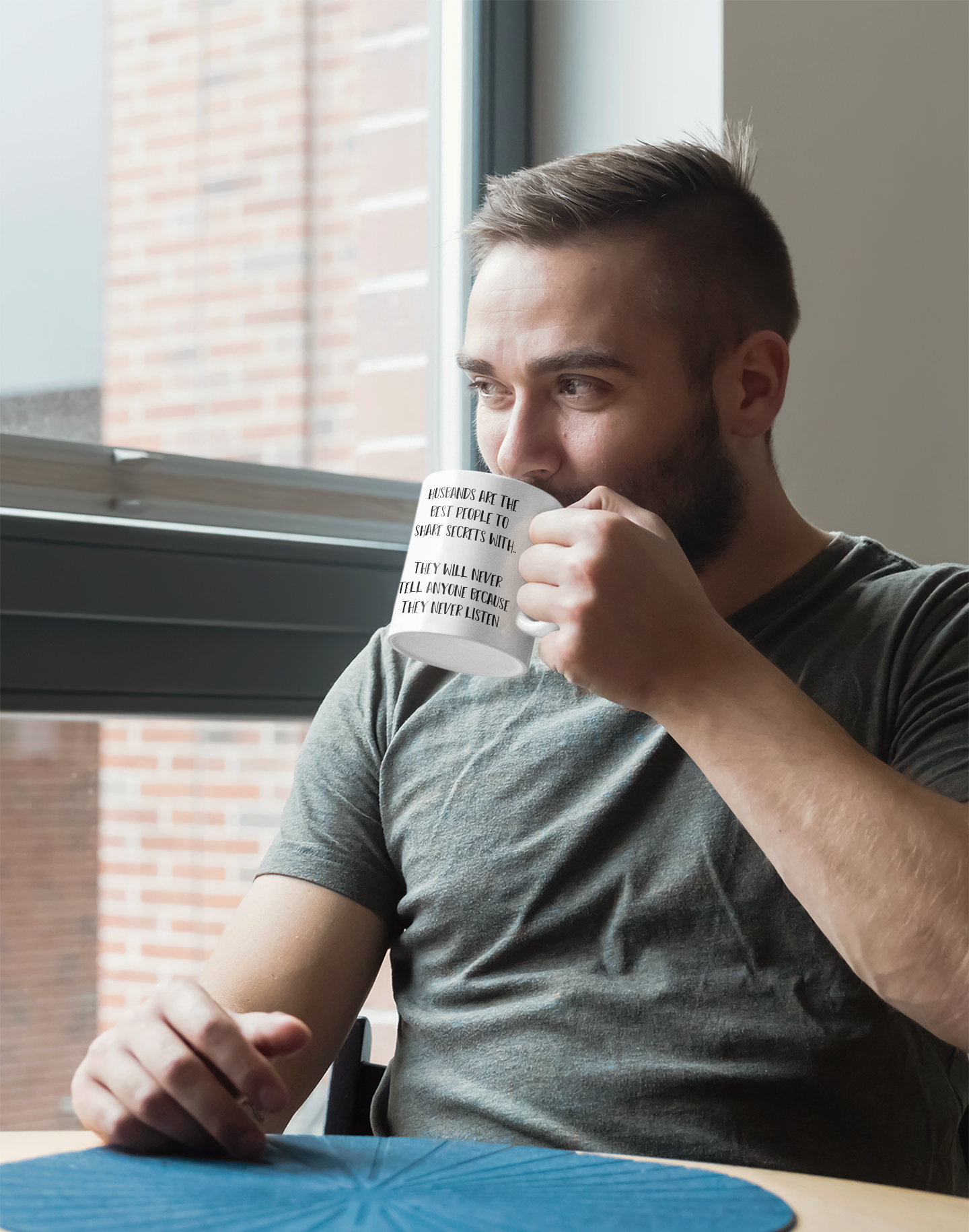 Man holding a white mug, featuring the funny quote 'husbands are the best people to share secrets with. They will never tell anyone because they never listen'. Printed in black ink.