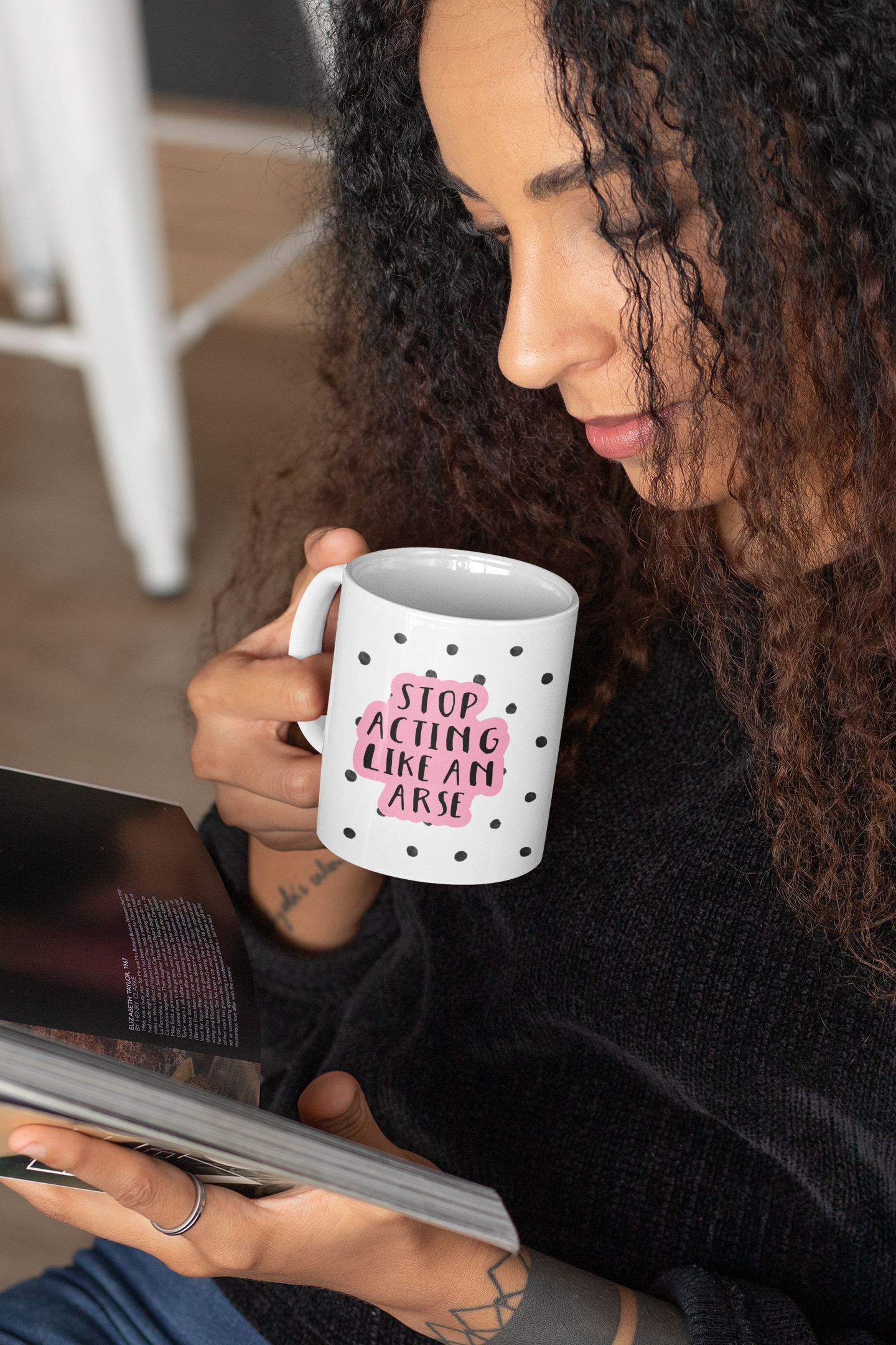 White ceramic mug with a black water-coloured spotty background & the quote 'stop acting like an arse' situated over the top. The wording is printed in black with a baby pink outline.