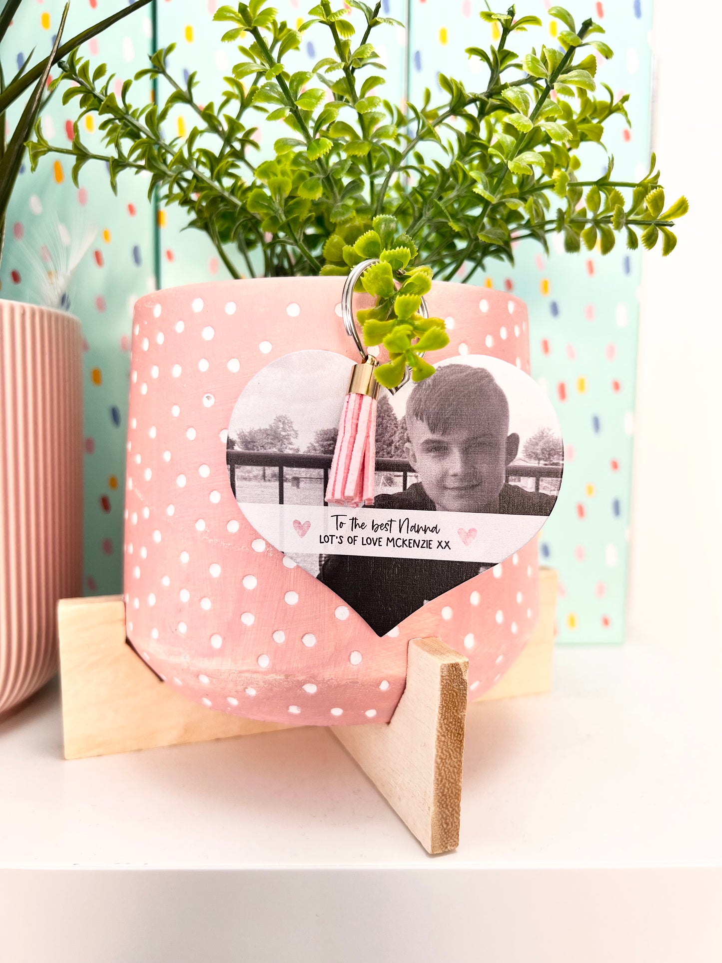 Mdf heart shaped keyring with a pink tassel, featuring a photo of a boy & a custom text underneath in a white banner which reads 'to the best nanna, lot's of love Mckenzie x'.