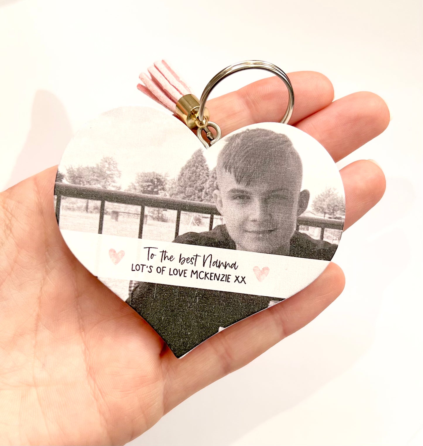 Mdf heart shaped keyring with a pink tassel, featuring a photo of a boy & a custom text underneath in a white banner which reads 'to the best nanna, lot's of love Mckenzie x'.