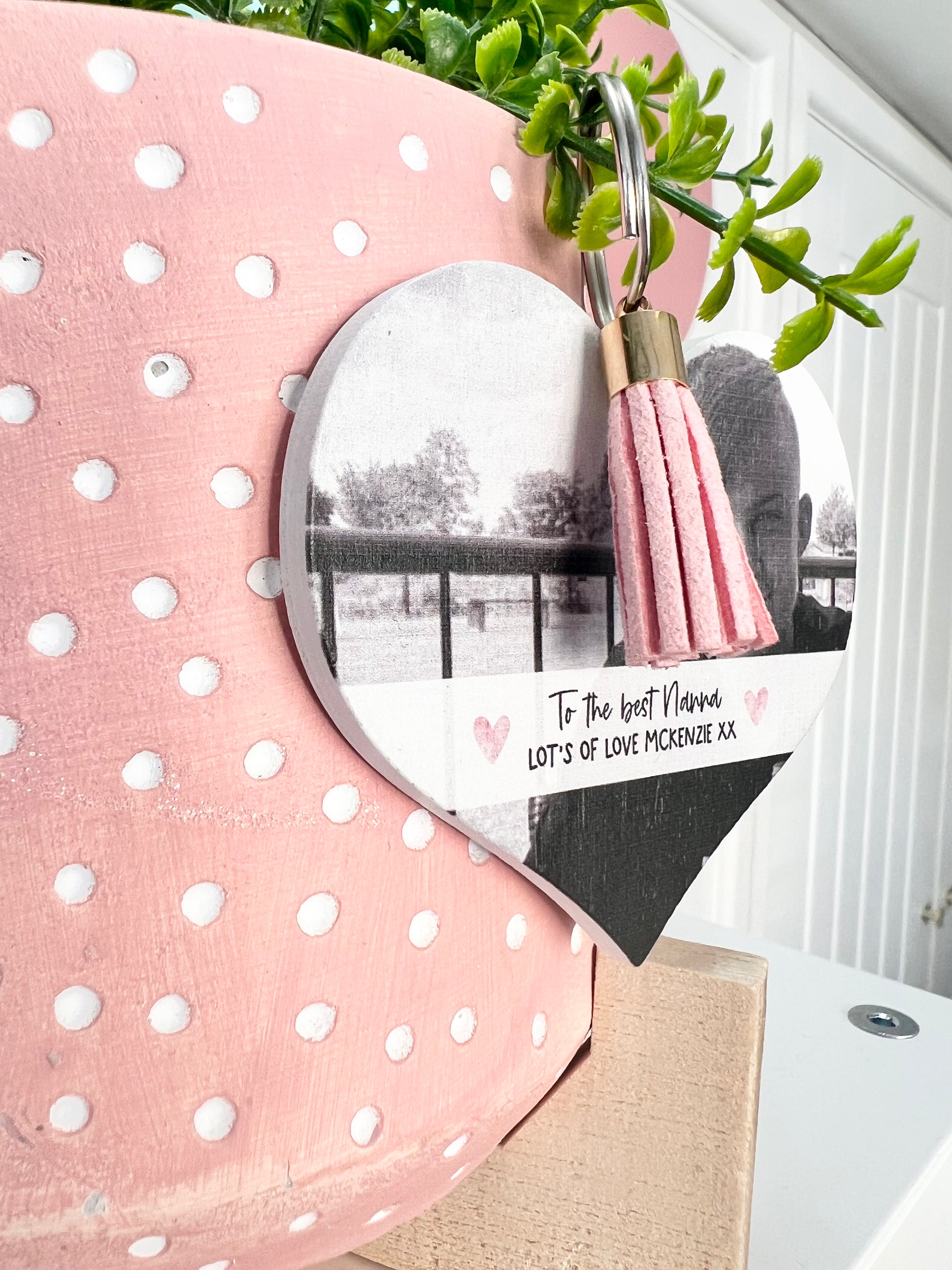 Mdf heart shaped keyring with a pink tassel, featuring a photo of a boy & a custom text underneath in a white banner which reads 'to the best nanna, lot's of love Mckenzie x'.