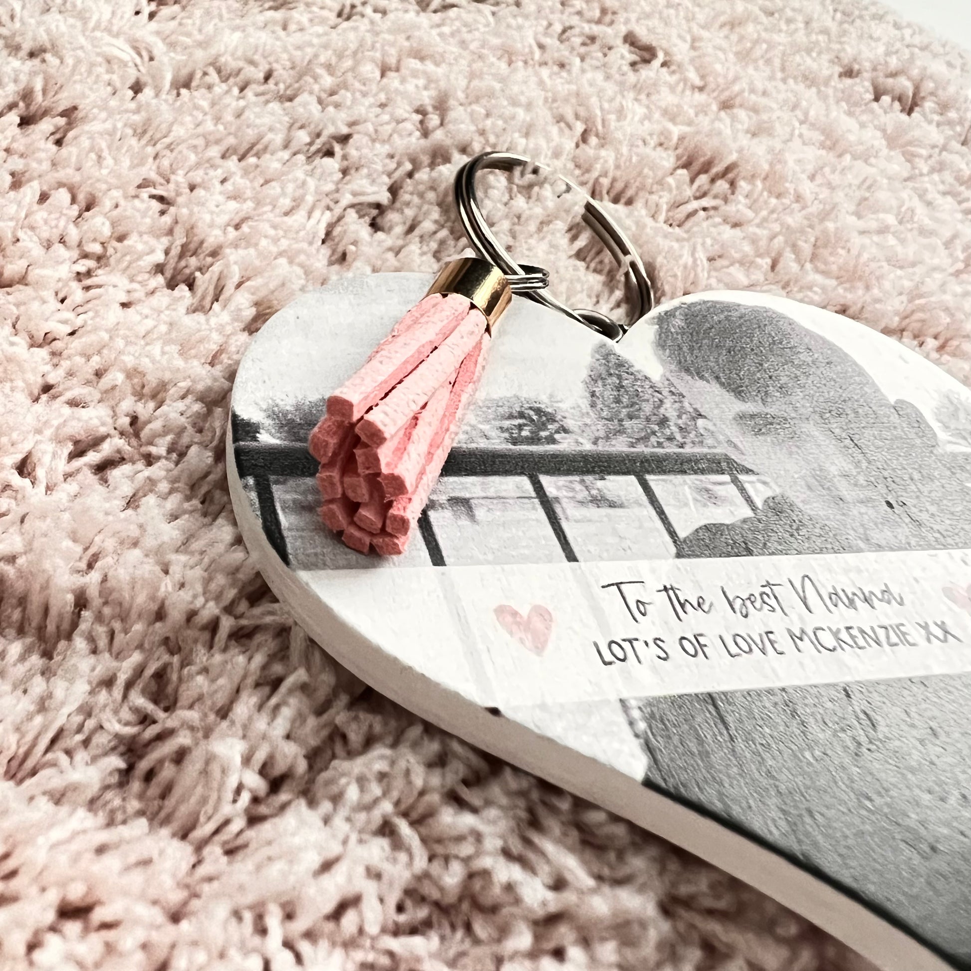 Mdf heart shaped keyring with a pink tassel, featuring a photo of a boy & a custom text underneath in a white banner which reads 'to the best nanna, lot's of love Mckenzie x'.
