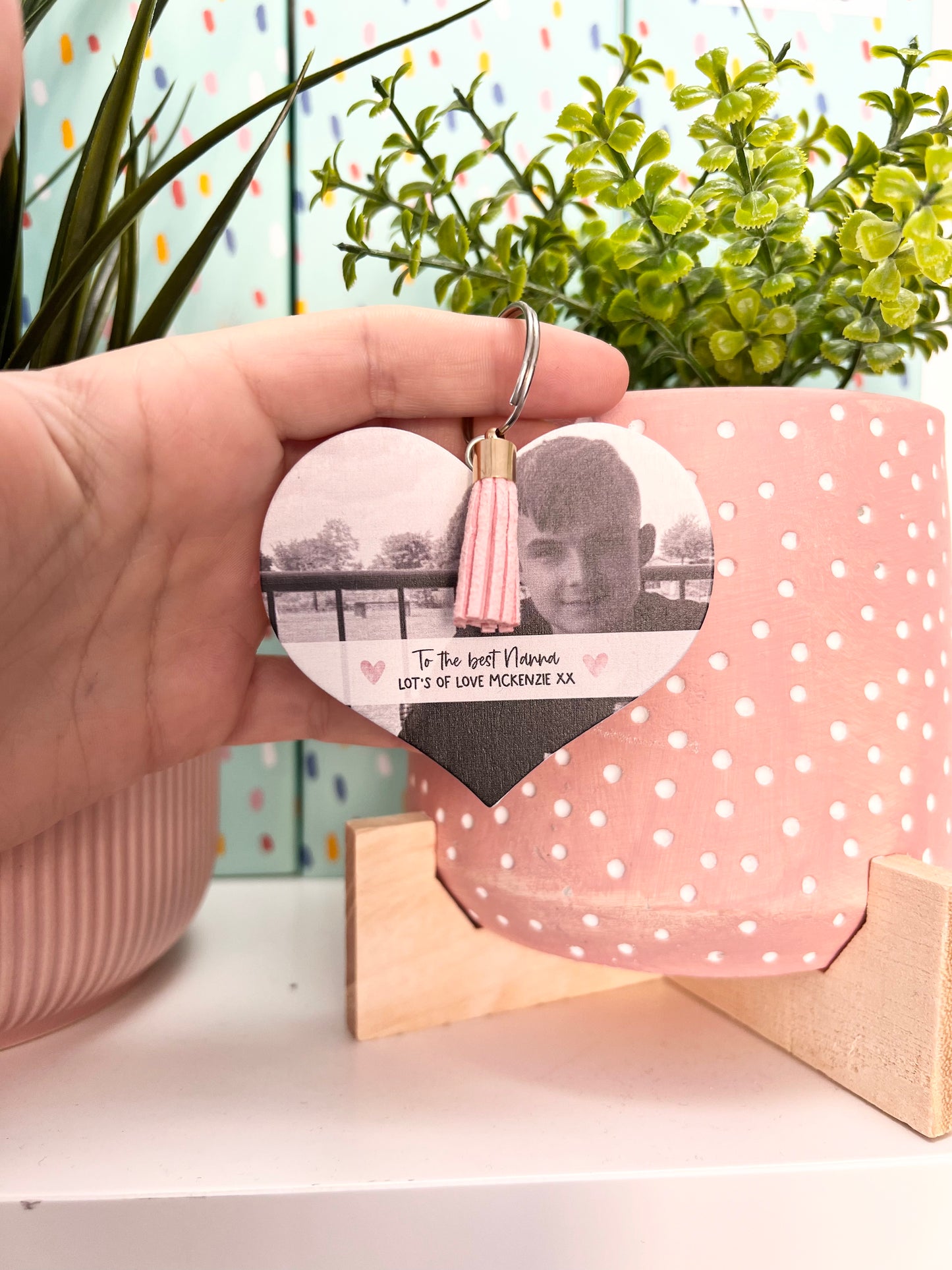 Mdf heart shaped keyring with a pink tassel, featuring a photo of a boy & a custom text underneath in a white banner which reads 'to the best nanna, lot's of love Mckenzie x'.