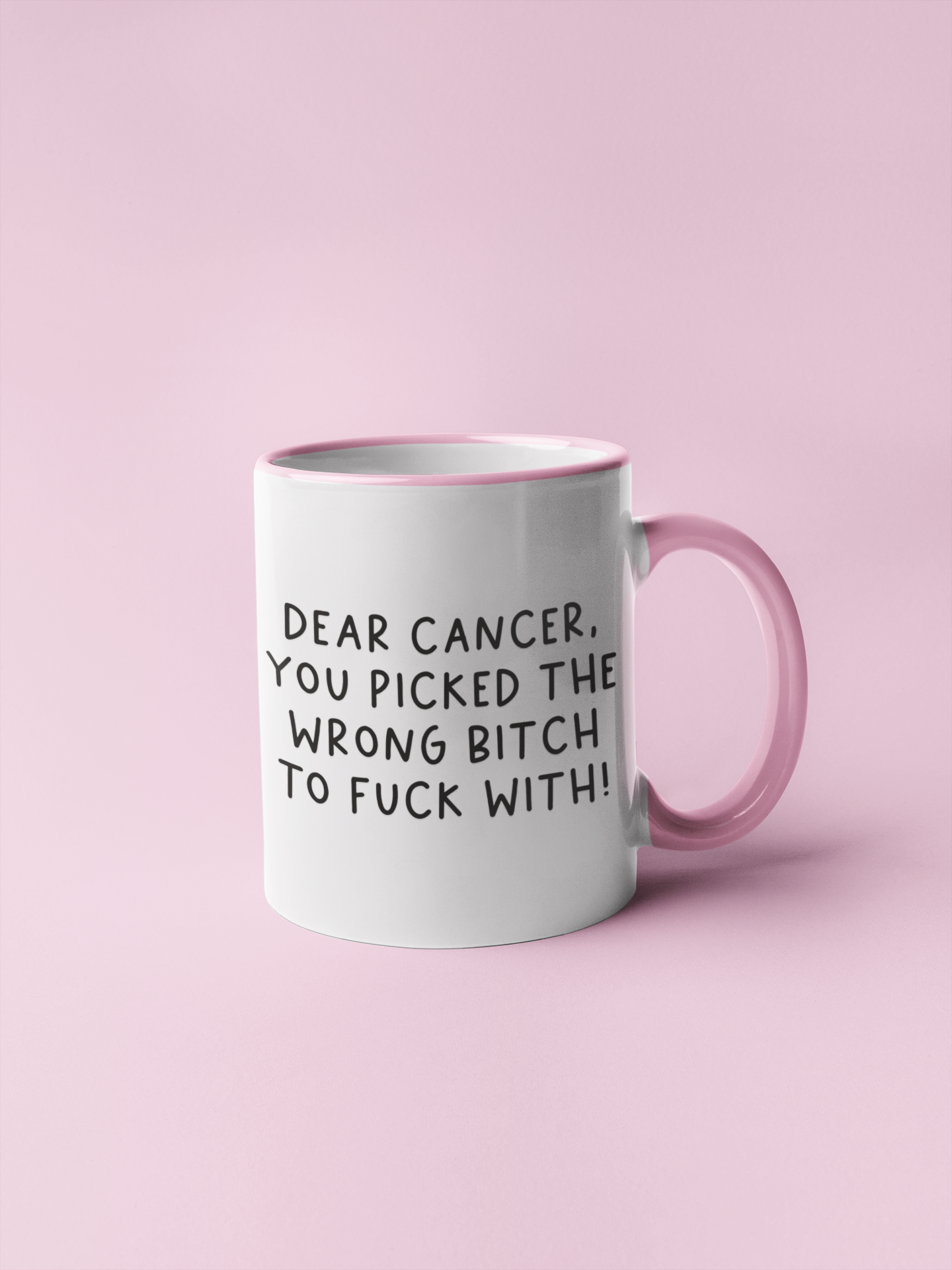 White mug with a pink inner & handle with the quote 'dear cancer, you picked the wrong bitch to fuck with' situated in the middle & printed in black.