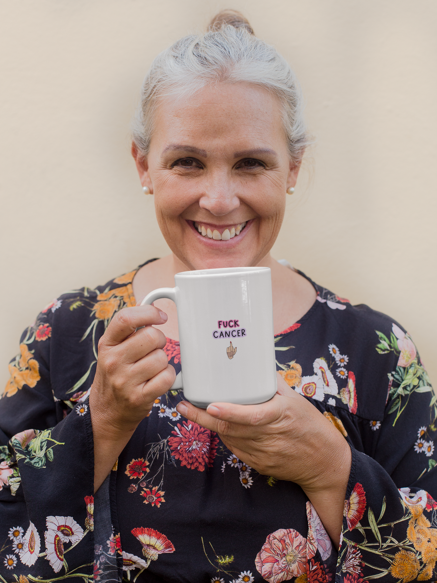 White mug with a middle finger clipart in the centre. Above the middle finger design is the words 'fuck cancer', printed in black with a pink & purple outline.