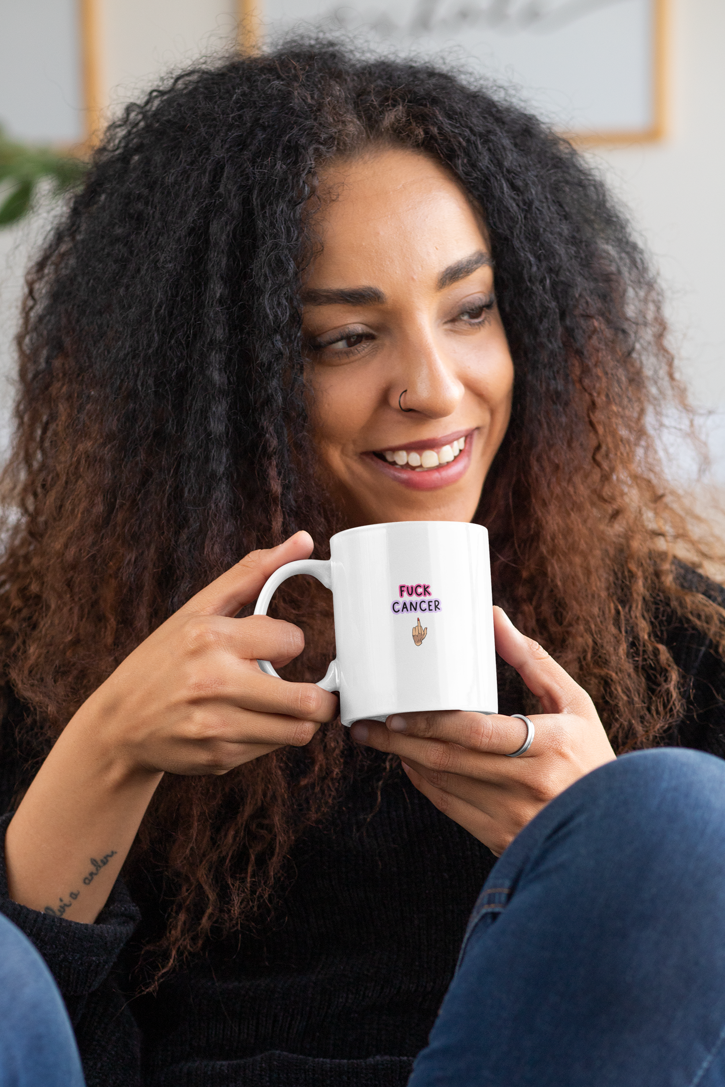 White mug with a middle finger clipart in the centre. Above the middle finger design is the words 'fuck cancer', printed in black with a pink & purple outline.