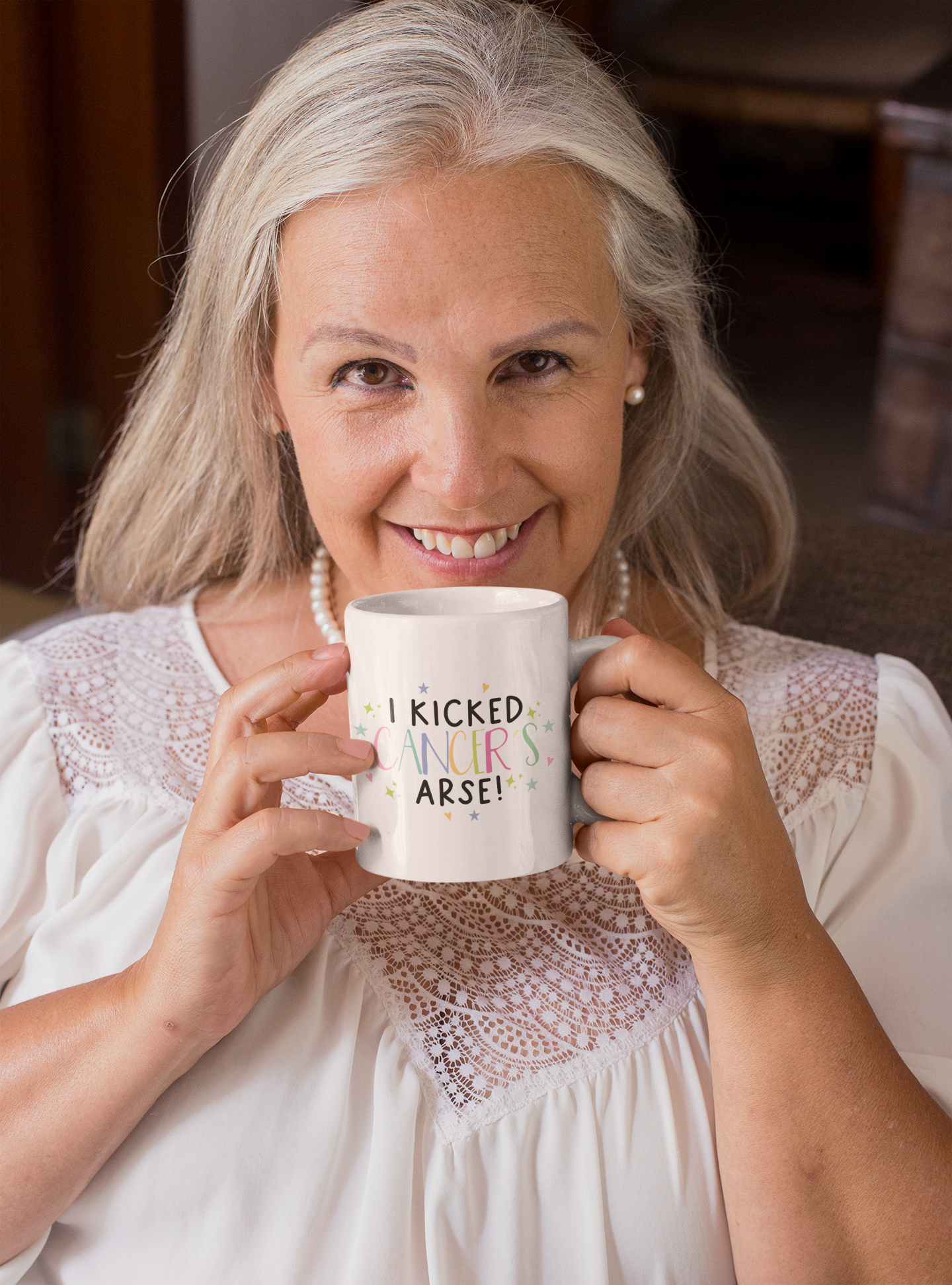 White mug with the words 'i kicked cancers arse! printed in the middle. Cancer is multicoloured pastel colours surrounded by little pastel stars & hearts.