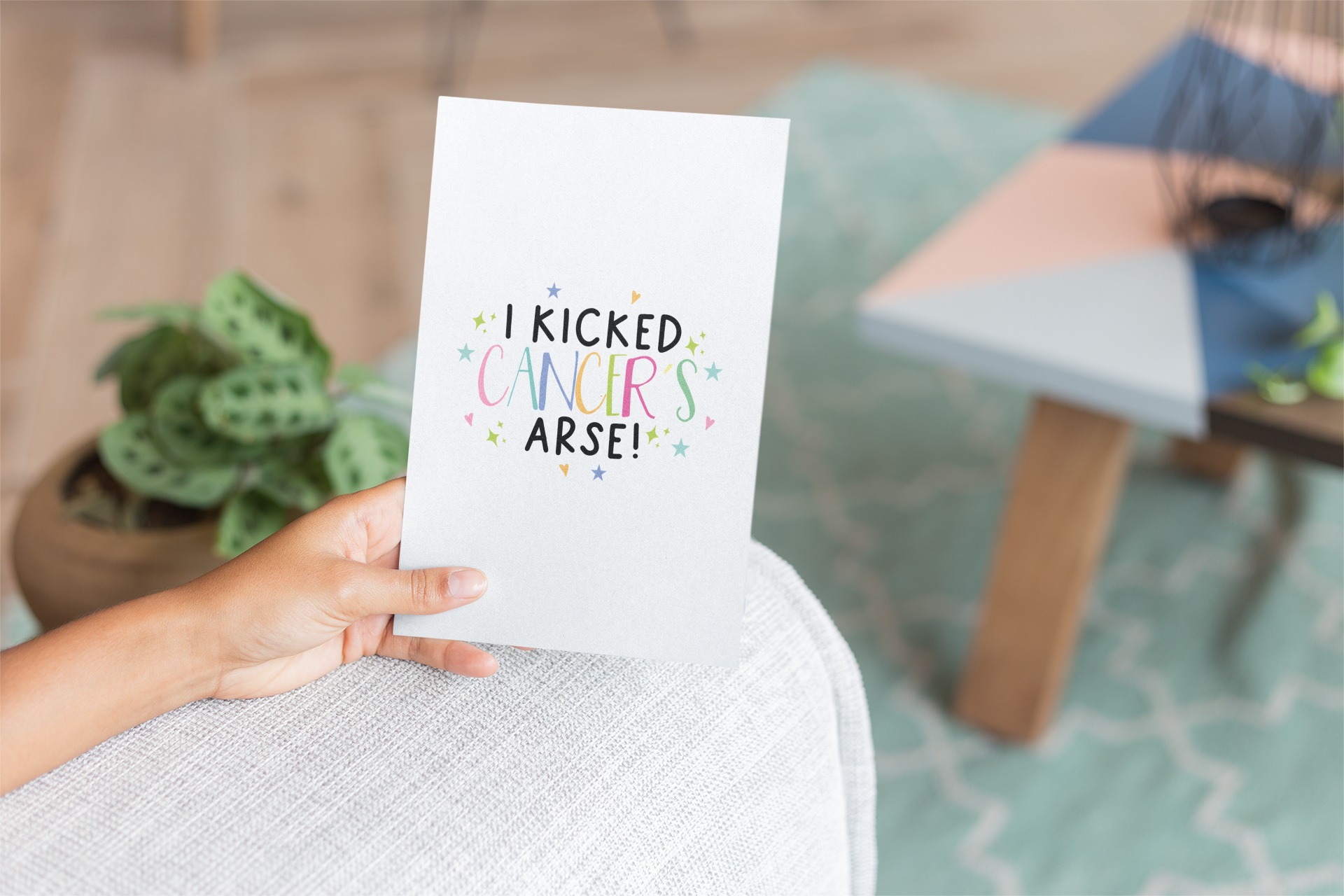 White vertical card with the words 'i kicked cancers arse!' printed in the middle. Cancer is multicoloured pastel colours surrounded by little pastel stars & hearts.
