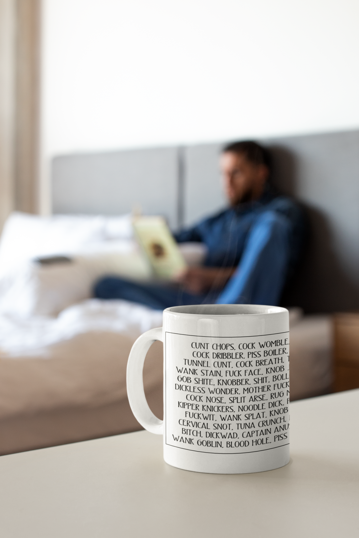 A white ceramic mug featuring a full wrap design with funny words printed throughout. The words include c*nt chops, twat waffle, cock womble, piss flaps, etc. Printed in black ink.