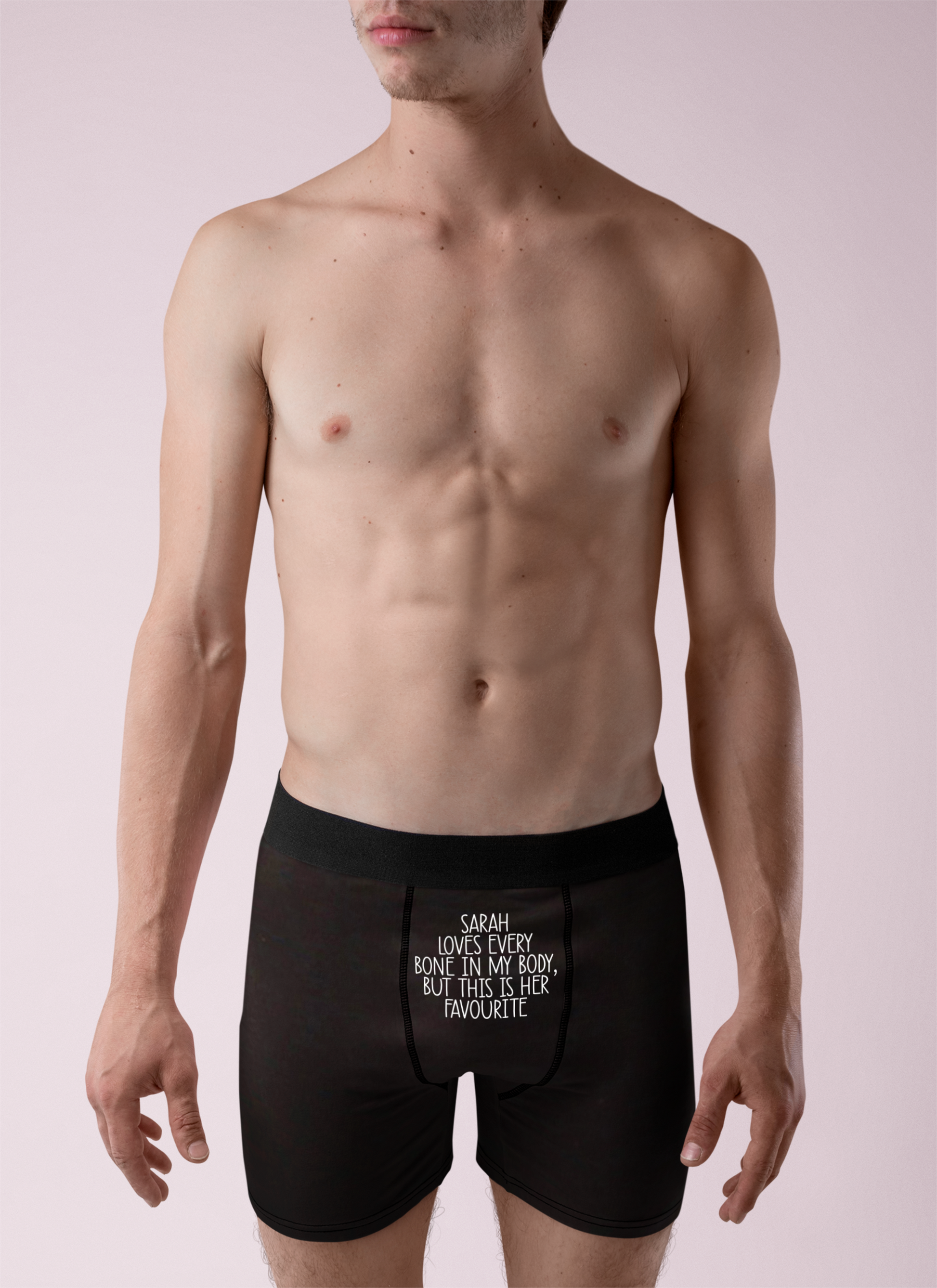 Black pair of mens boxer short pants with a white funny quote to the top middle section. It reads '(name) loves every bone in my body... but this is her favourite'.