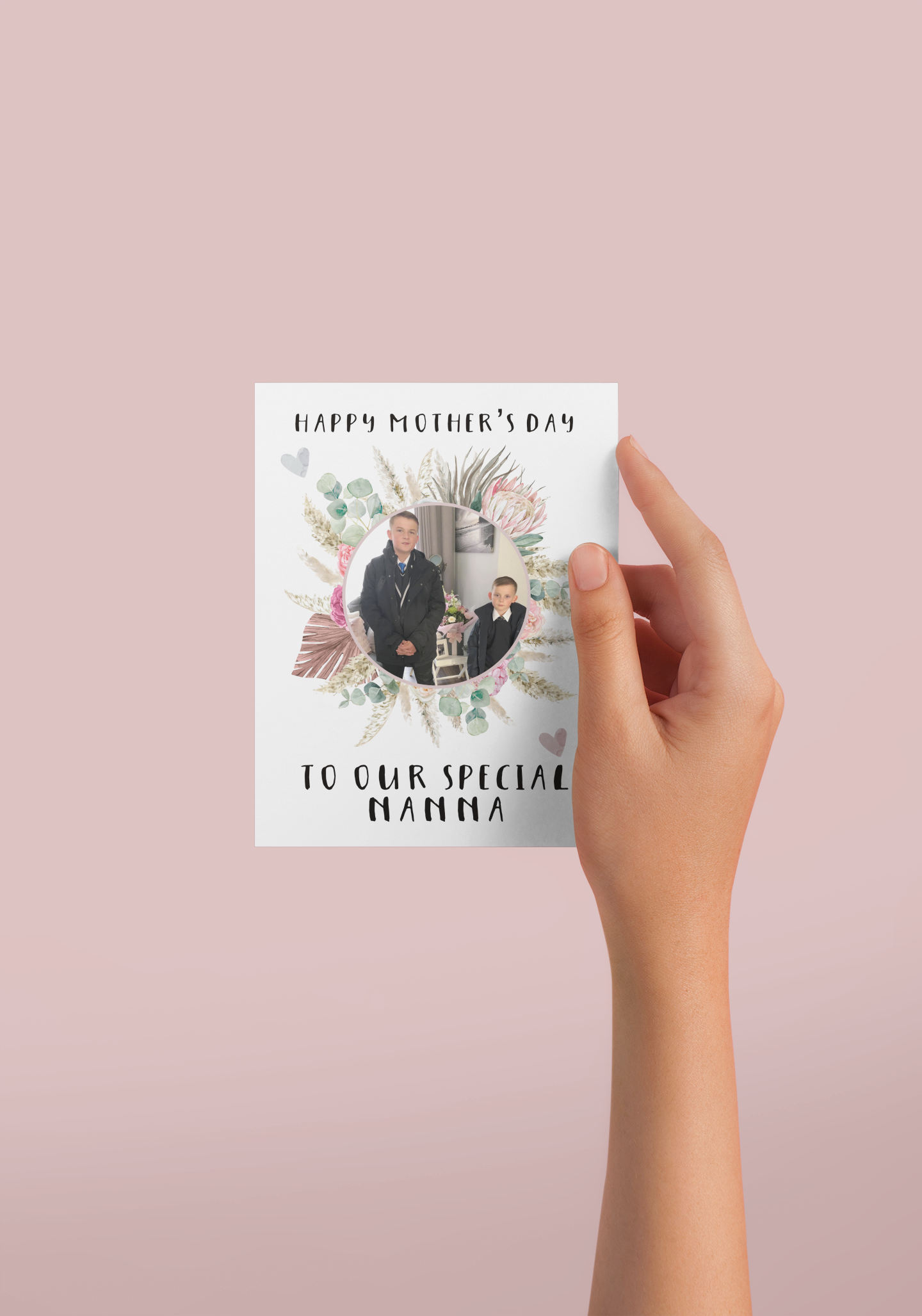 A white greetings card which has a colourful floral design wreath with a personalised photo of 2 children in the middle. To the top of the flower is the words 'happy mother's day.' and to the bottom 'to our special nanna' Printed in black ink.