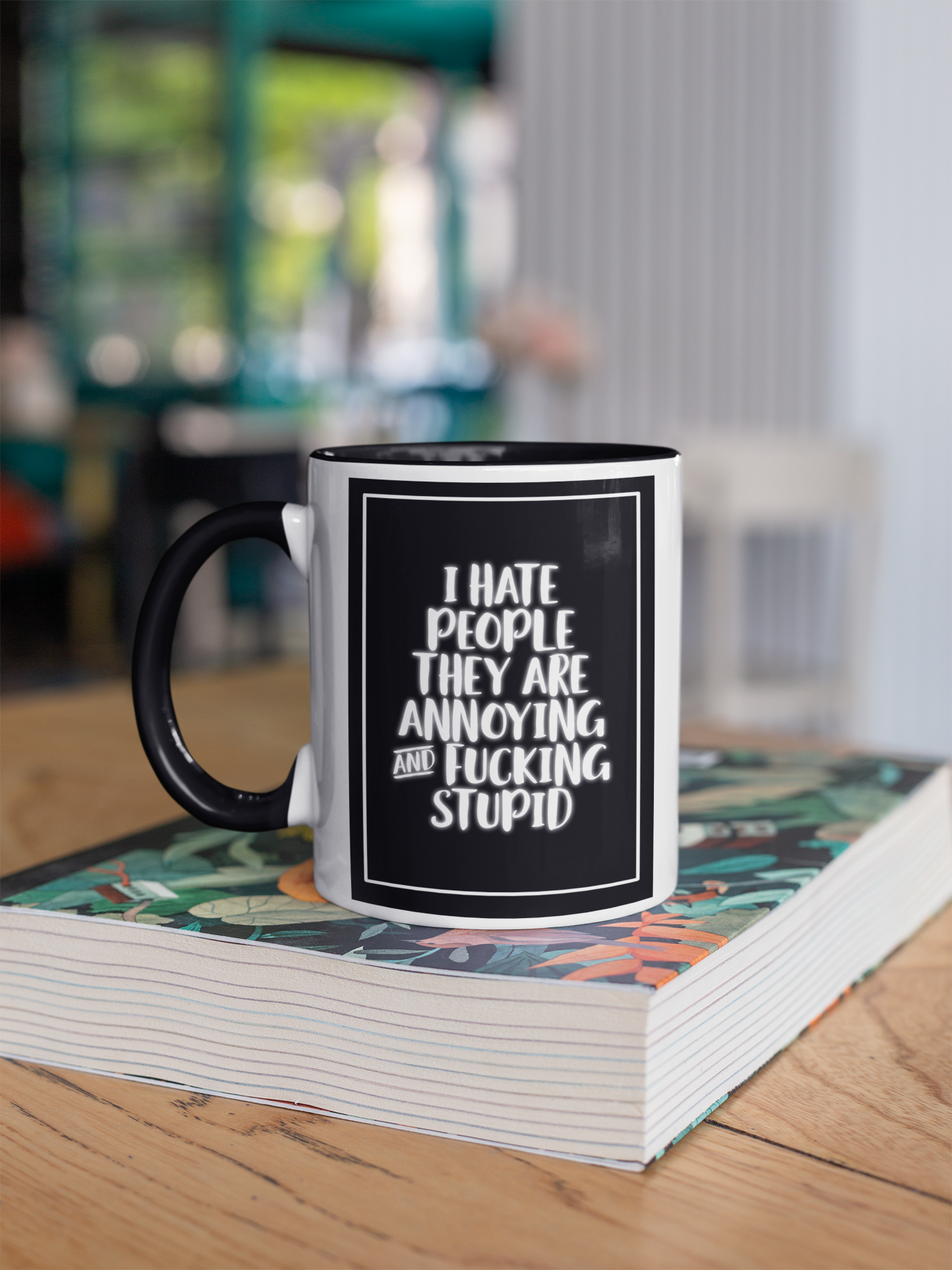 White mug with a black handle and rim with the quote i hate people they are annoying and fucking stupid printed in white over a black background.