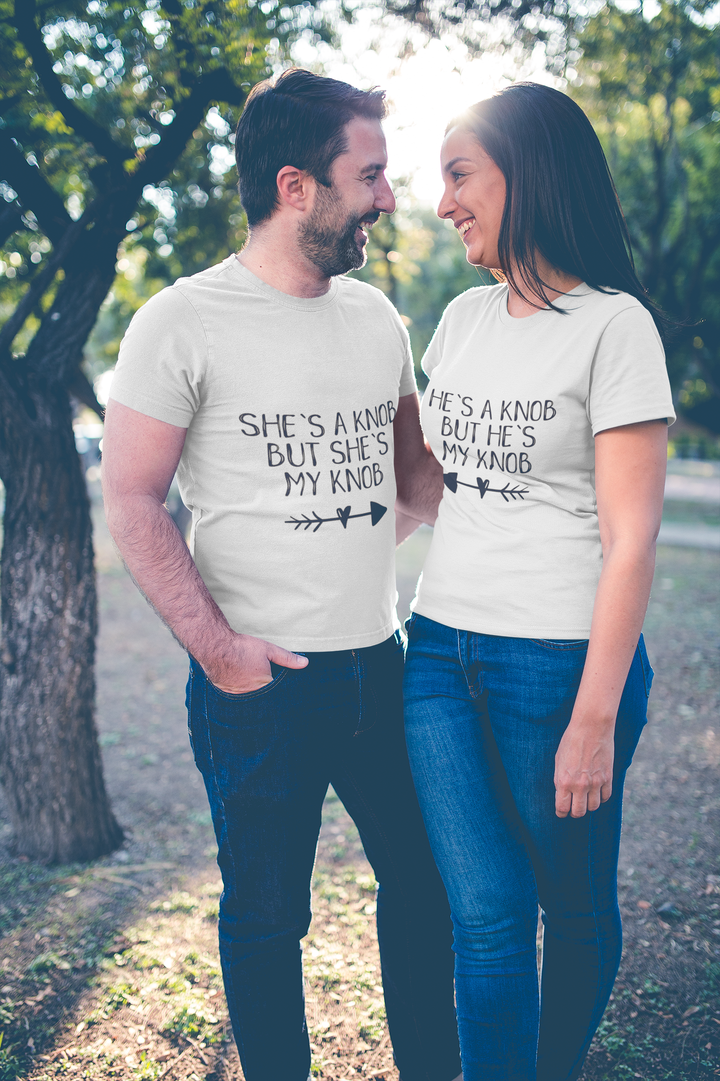 A man & woman wearing white matching t-shirts with the funny quotes 'he's a knob but he's my knob' and 'she's a knob but she's my knob'. Printed in black ink.