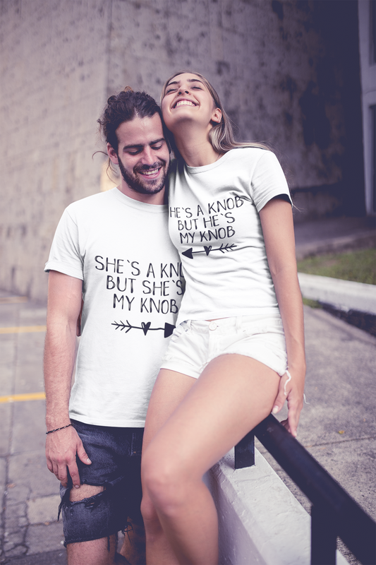 A man & woman wearing white matching t-shirts with the funny quotes 'he's a knob but he's my knob' and 'she's a knob but she's my knob'. Printed in black ink.