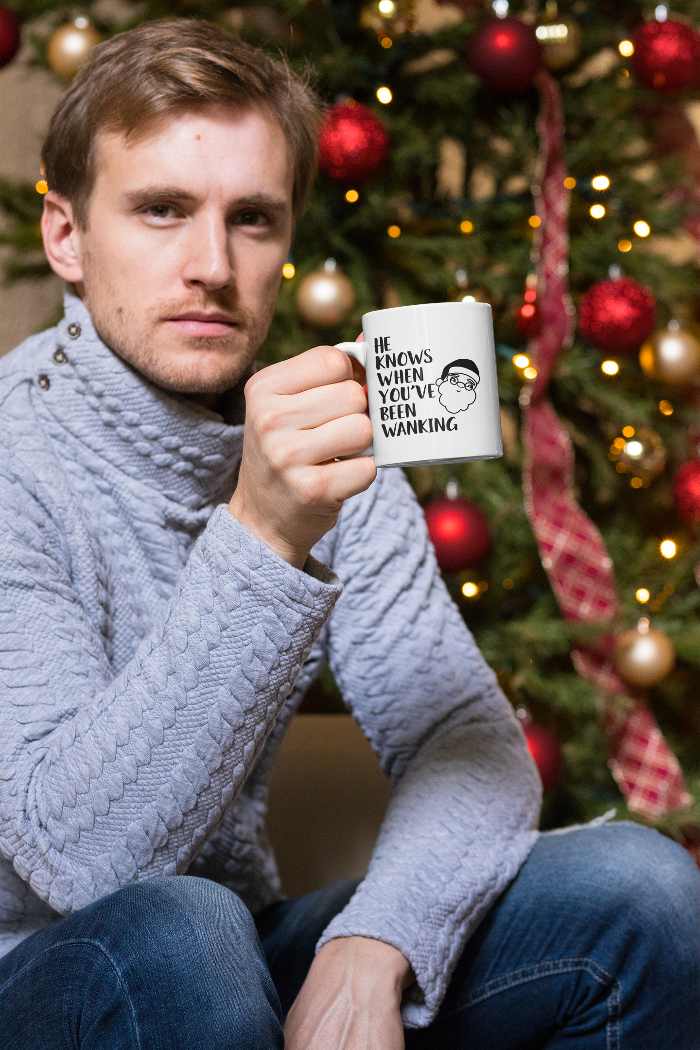 White mug with a cartoon santa head with the words 'he knows when you've been wanking' printed to the left side.