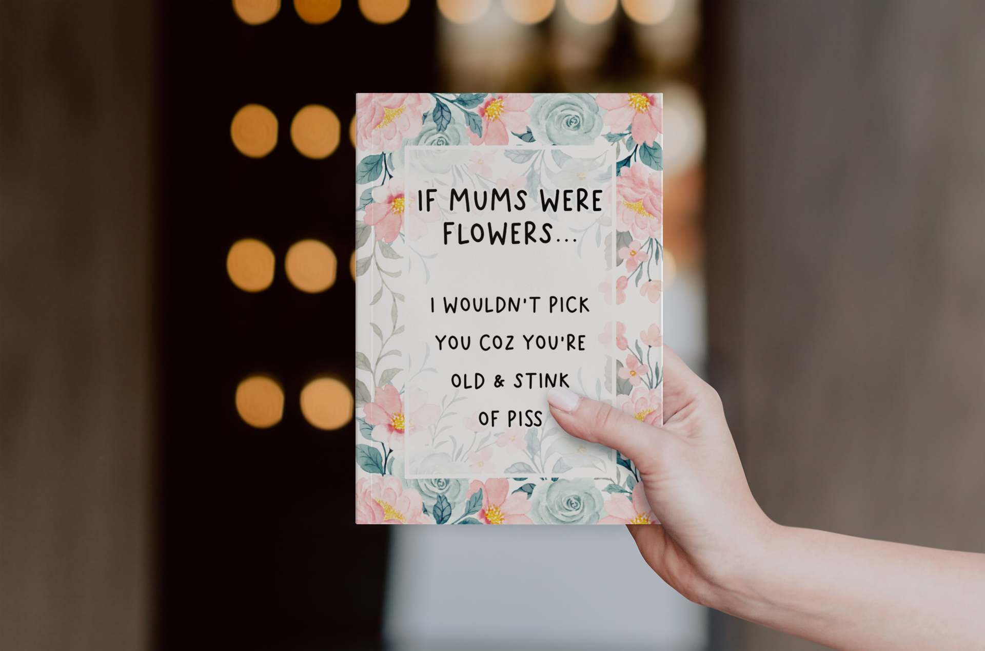 Greetings card with a pastel colour floral design to the front with the quote 'if mums were flowers... i wouldn't pick you coz you're old & stink of piss' printed in the middle in black ink.