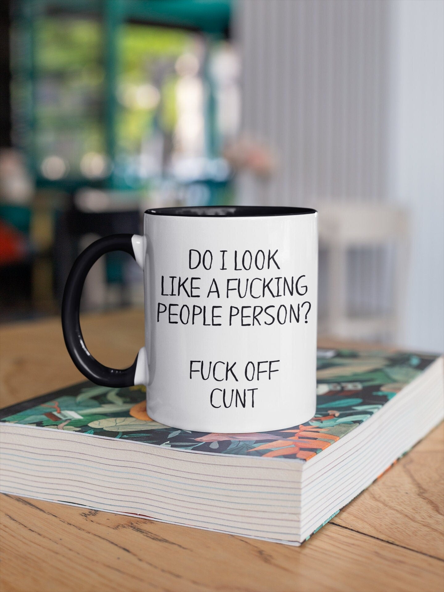 A white ceramic mug with a black handle featuring the funny quote ‘do i look like a fucking people person? Fuck off c*nt’. Printed in black ink.