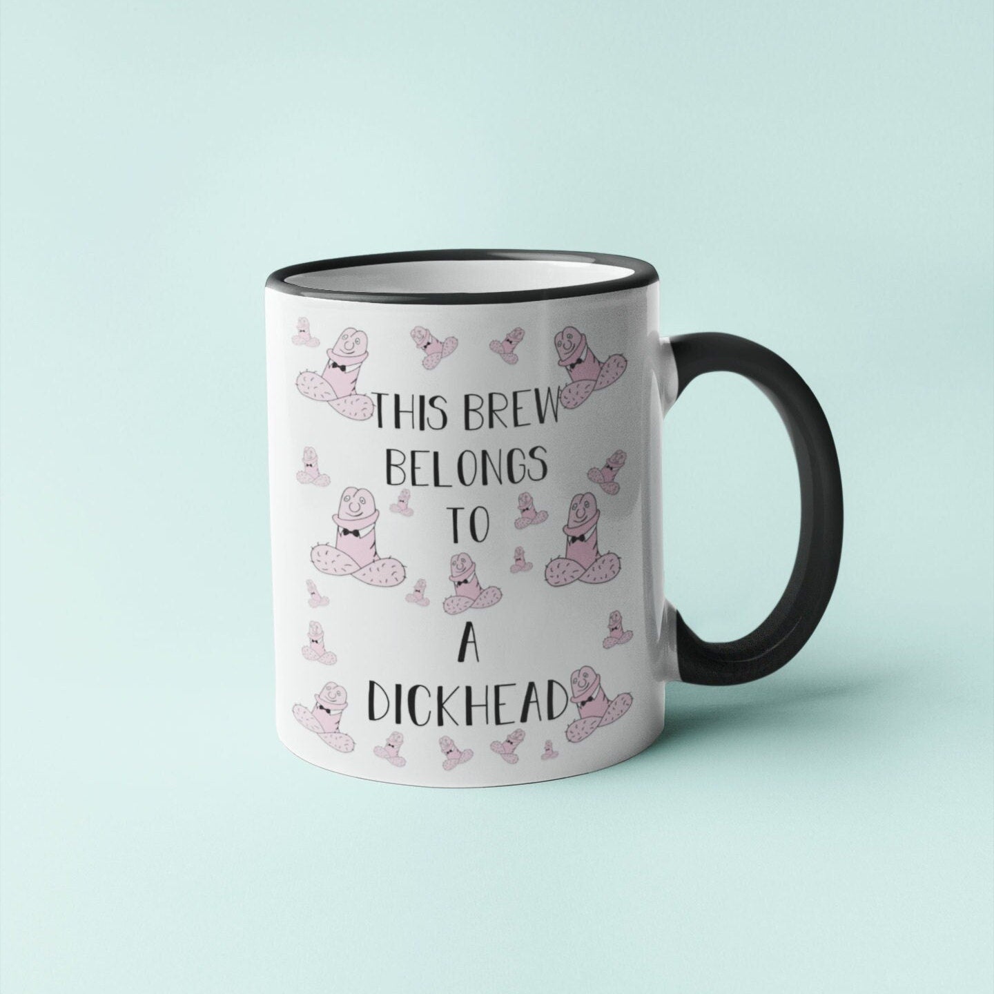 White ceramic mug with a black handle & a funny penis design printed to the front. Includes the quote 'this brew belongs to a dickhead'. Printed in black ink.
