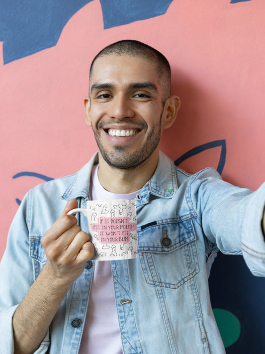 A white mug featuring a fun willy design print to the front. Over the print is a funny quote 'if it won't fit in your mouth, it won't fit in your bum', printed in black & pink ink