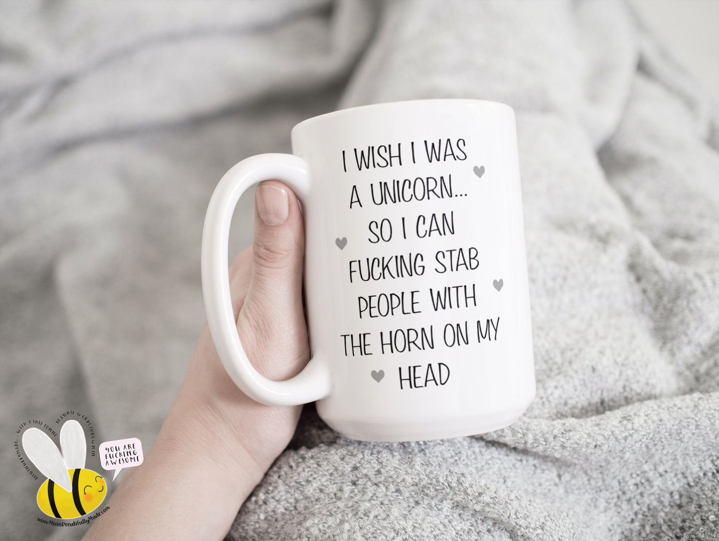 A white ceramic mug featuring the funny quote ‘I wish i was a unicorn... So i can fucking stab people with the horn on my head’. Printed in black ink with little grey hearts surround the text.