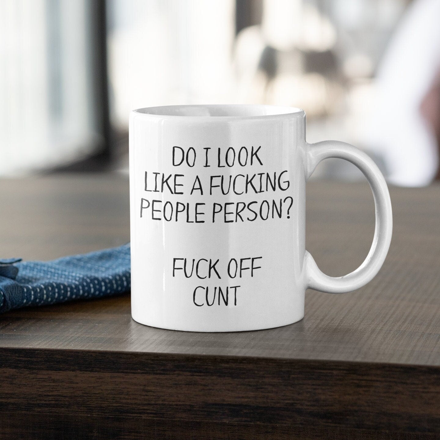 A white ceramic mug featuring the funny quote ‘do i look like a fucking people person? Fuck off c*nt’. Printed in black ink.