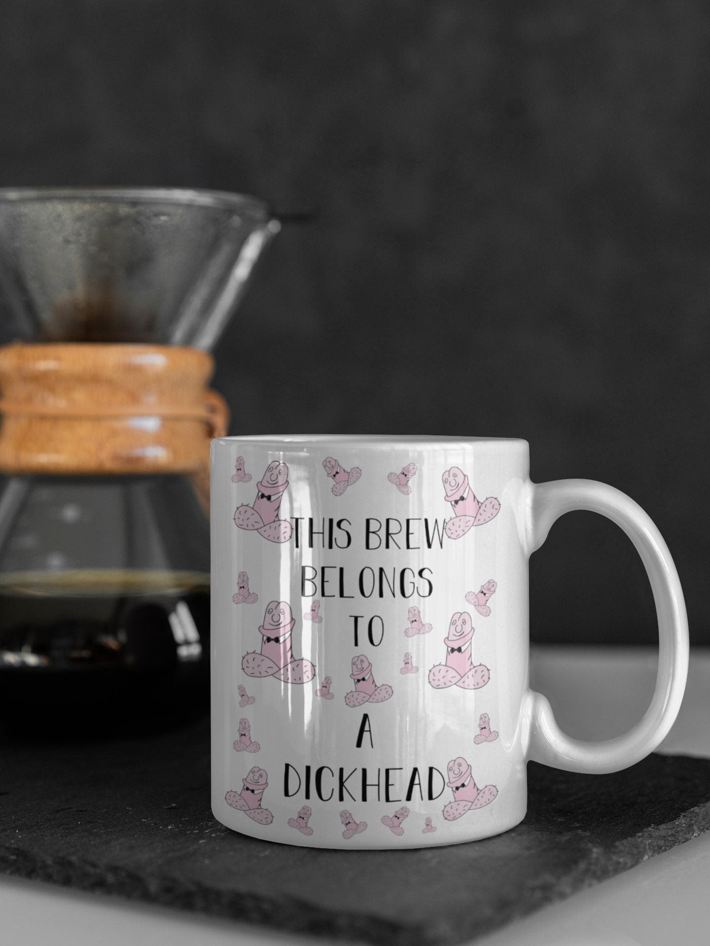 White ceramic mug with a funny penis design printed to the front. Includes the quote 'this brew belongs to a dickhead'. Printed in black ink.