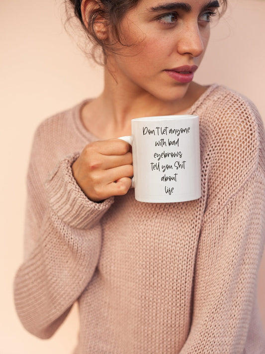 A white ceramic mug featuring a funny profanity quote don't let anyone with bad eyebrows tell you shit about life. Printed to the front in black ink.A white ceramic mug with a pink handle featuring the funny quote ‘yes i'm still in my pj's. What have i accomplished today? Fuck all’. Printed in black ink with a black heart.