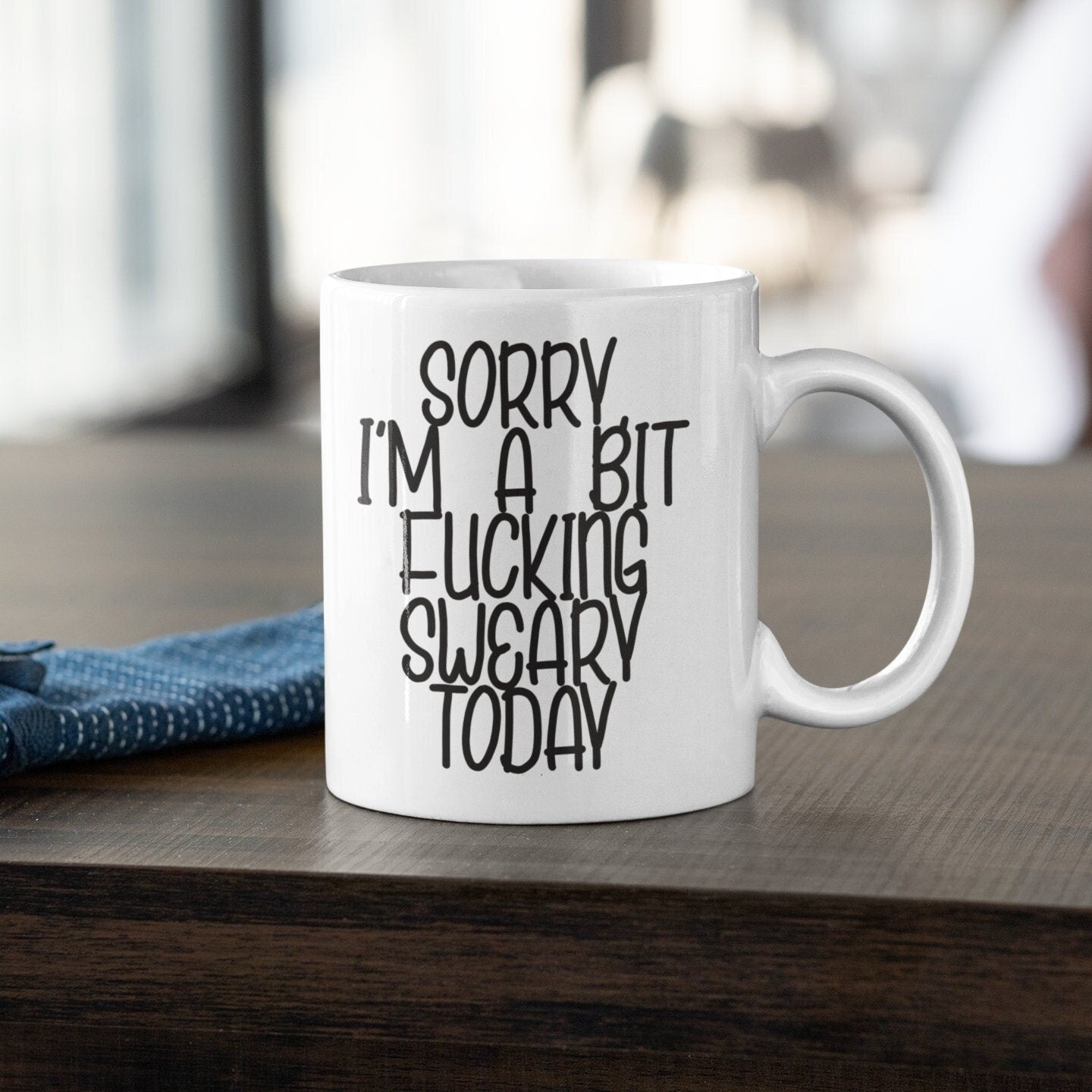A white ceramic mug with a black handle, featuring the funny quote 'sorry i'm a bit fucking swearing today'. Printed in black ink.