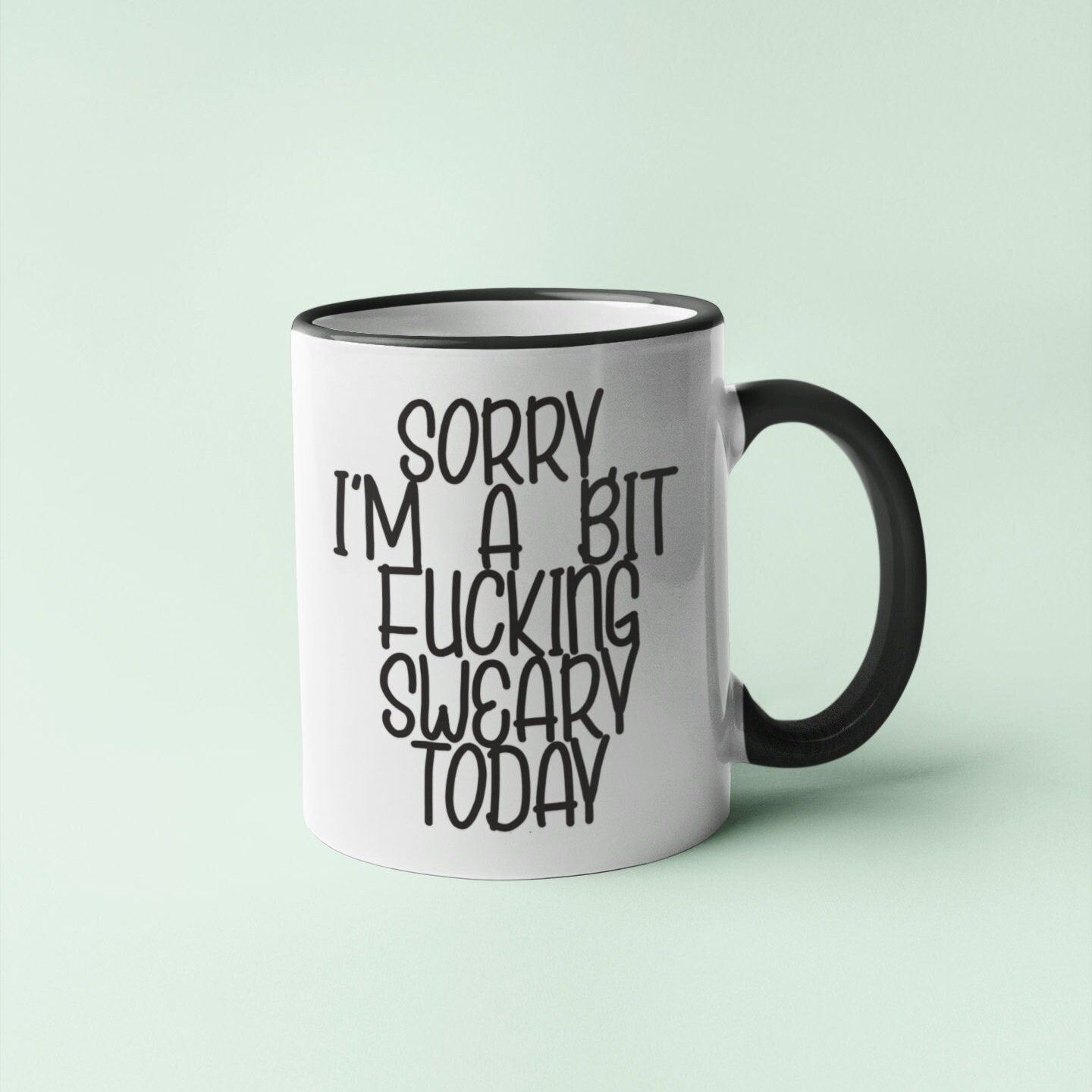 A white ceramic mug with a black handle, featuring the funny quote 'sorry i'm a bit fucking swearing today'. Printed in black ink.