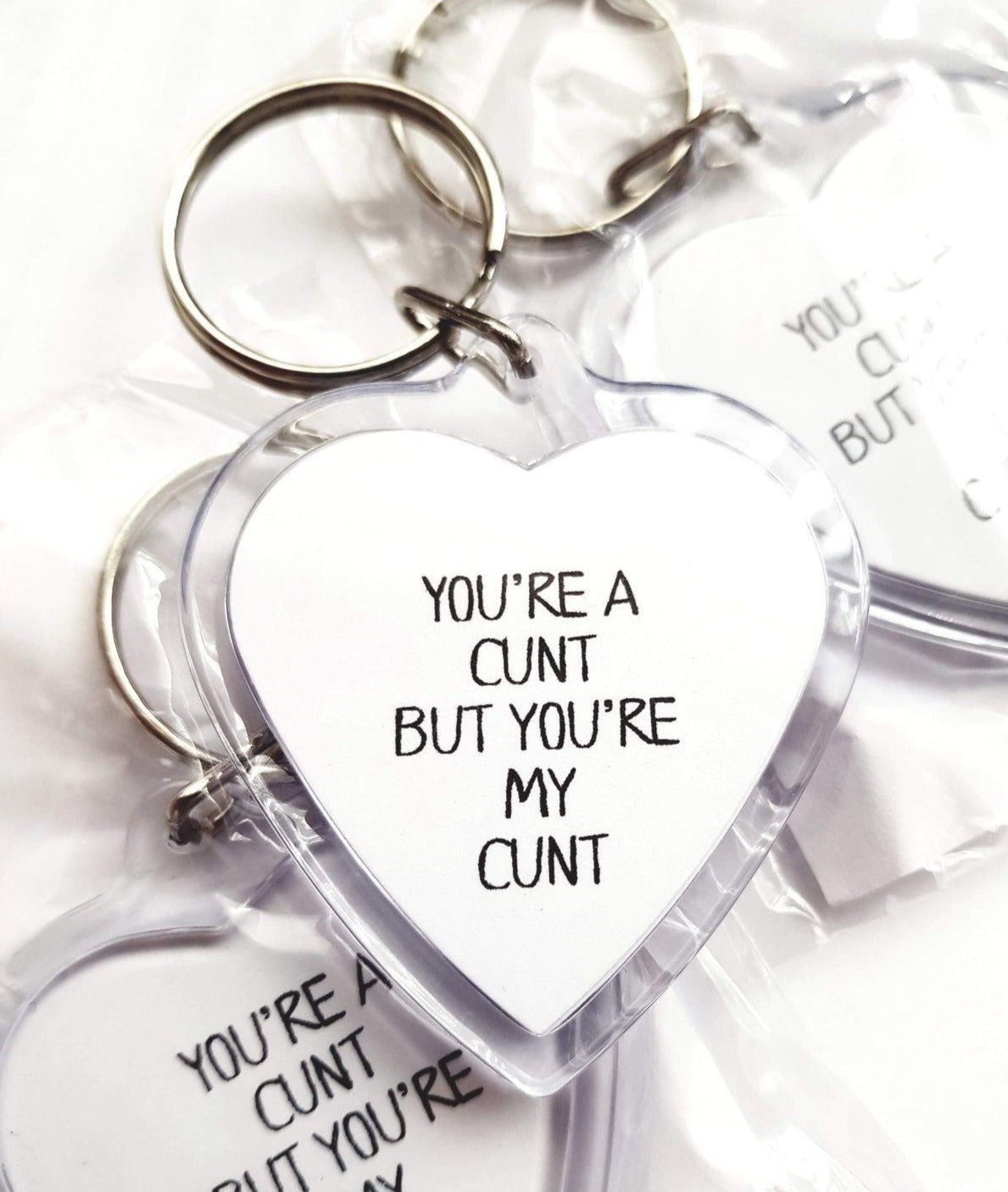 Acrylic heart keyring featuring the funny design 'you're a c*nt, but you'r my c*nt'.