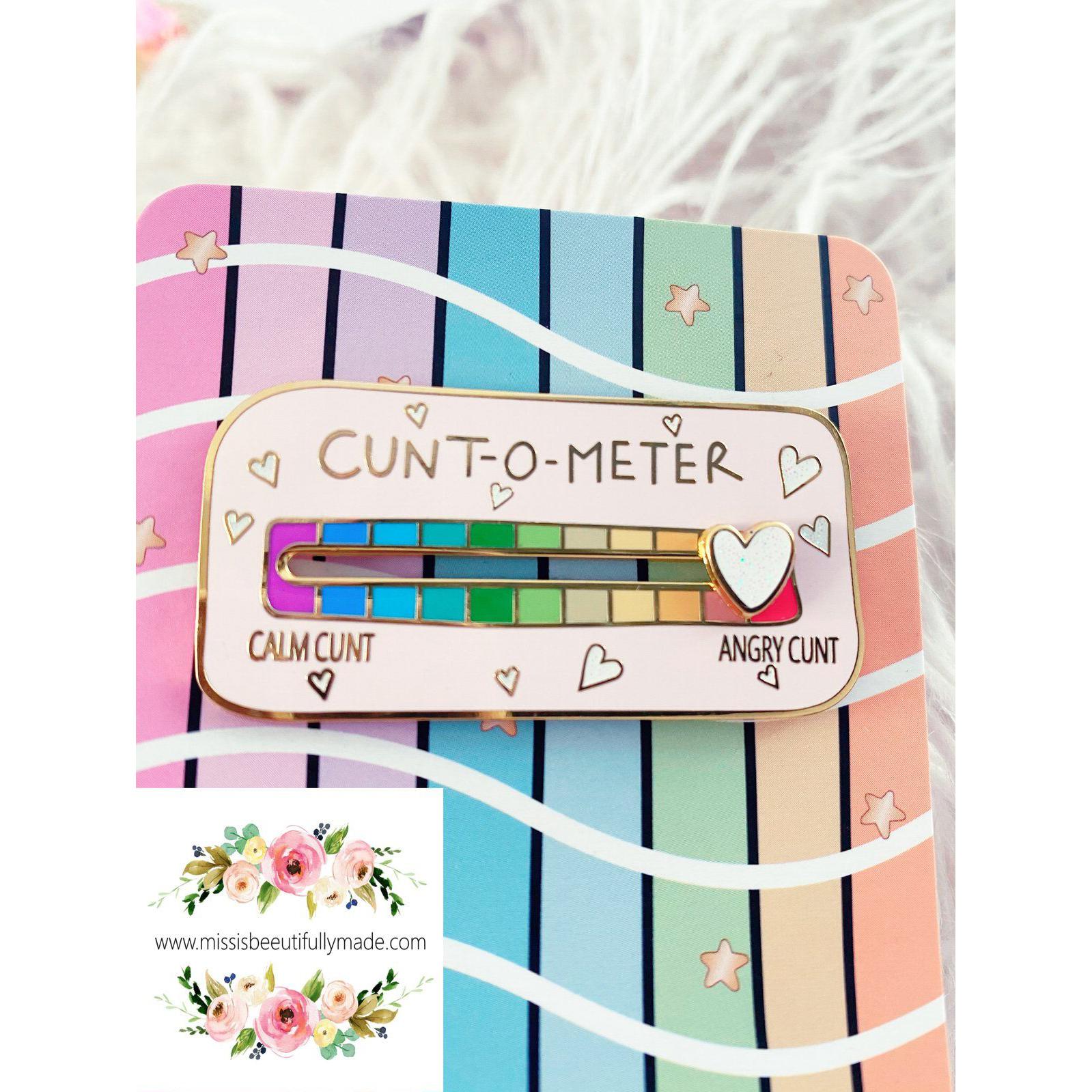 Gold enamel cunt-o-meter pin badge with a white glittery sliding heart. Slide from calm cunt to angry cunt with this funny interactive pin badge with pretty pastel rainbow colours.