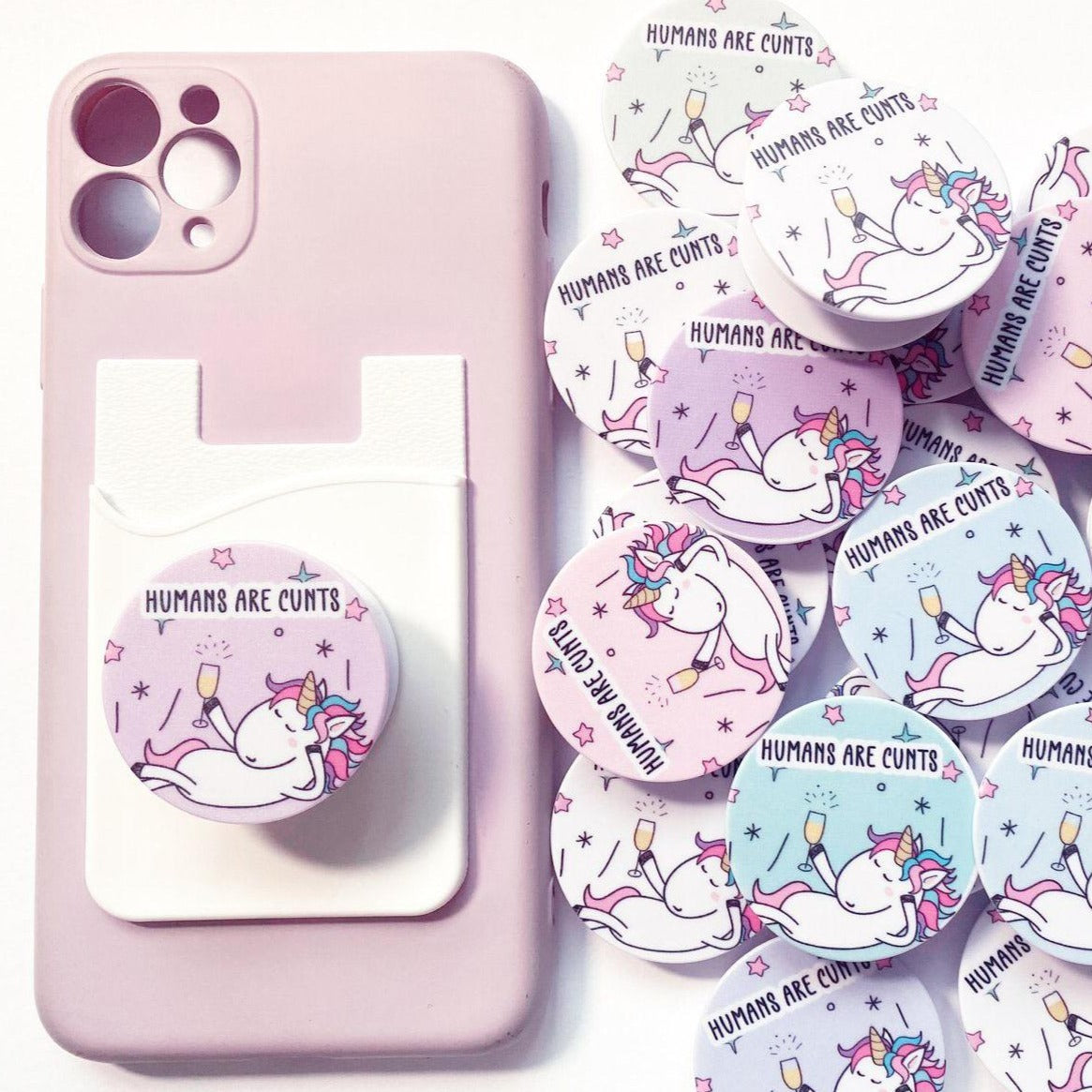 A round phone case popper with a cute stars & unicorn design to the front & the quote 'humans are c*nts' to the top.
