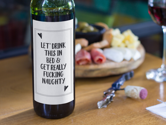 A bottle of wine featuring a custom label which reads 'let's drink this in bed & get really fucking naughty'. Printed in black ink.