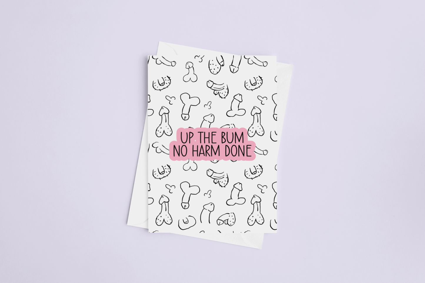A white folded greetings card & envelope featuring a fun willy design print to the front. Over the print is a funny quote 'up the bum, no harm done', printed in black & pink ink
