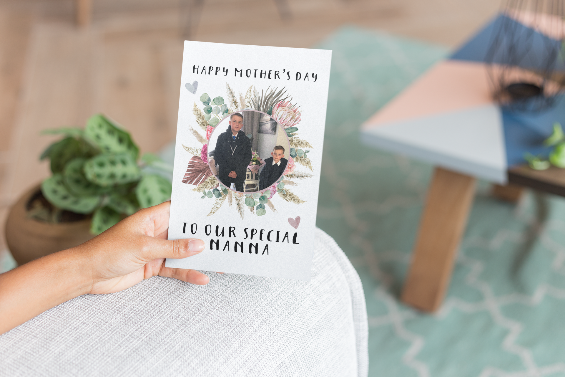 A white greetings card which has a colourful floral design wreath with a personalised photo of 2 children in the middle. To the top of the flower is the words 'happy mother's day.' and to the bottom 'to our special nanna' Printed in black ink.