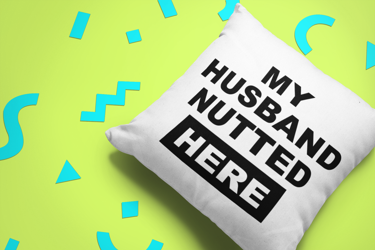White, square cushion with bold text to the front saying 'my husband nutted here'.