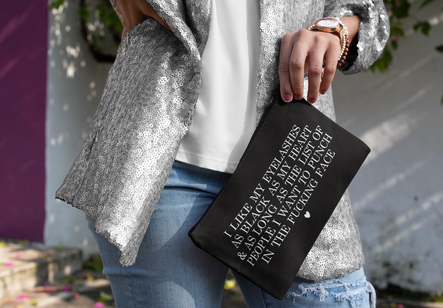 Black cosmetic bag featuring a funny quote in a bold text which reads 'i like my eyelashes as black as my heart & as long as the list of people i want to punch in the fucking face.' Printed in white.