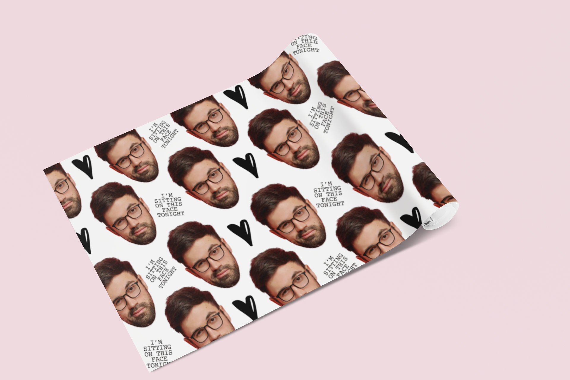 A roll of white gift wrap featuring a cut out face of a man & a funny quote 'i'm sitting on this face tonight' printed through out.