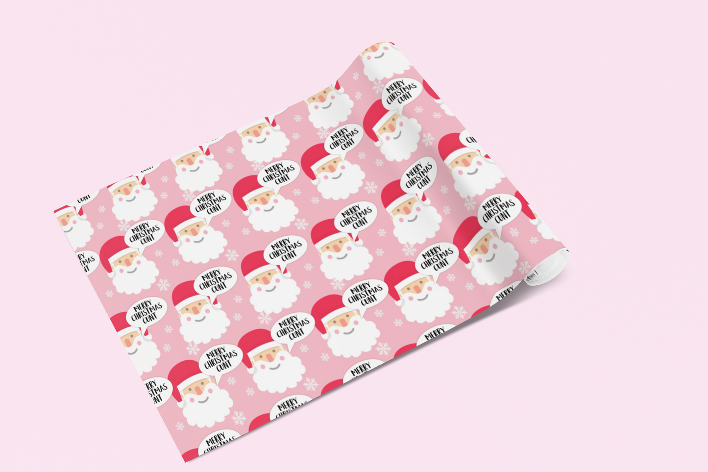A roll of gift wrap laid out on to a pink surface. Features a funny repetitive quote 'merry christmas you c*nt' in speech bubbles, with santa heads on a pink background.