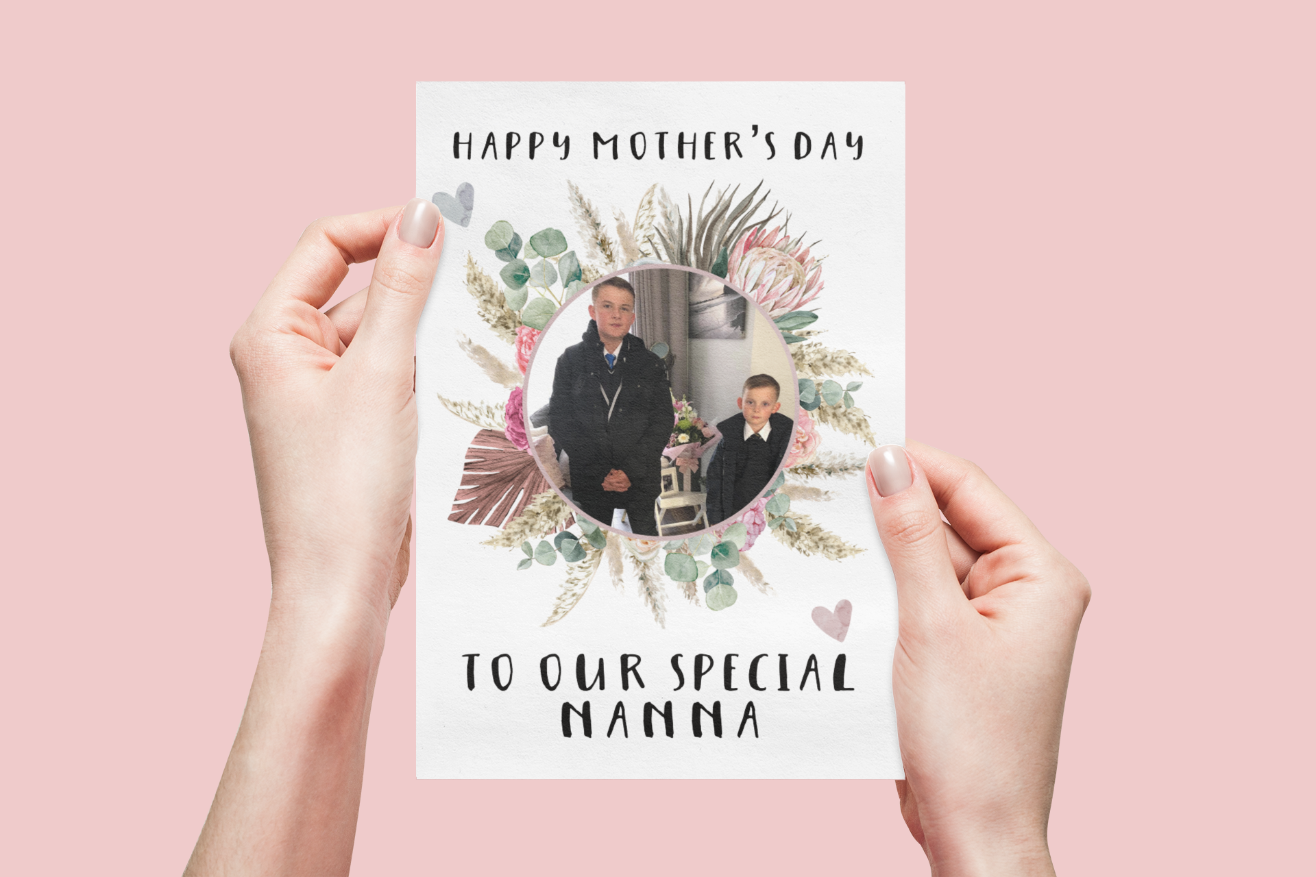A white greetings card which has a colourful floral design wreath with a personalised photo of 2 children in the middle. To the top of the flower is the words 'happy mother's day.' and to the bottom 'to our special nanna' Printed in black ink.