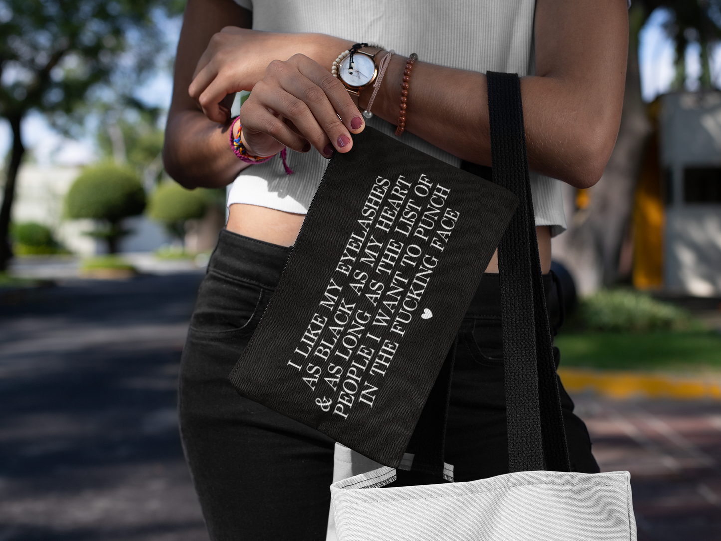 Black cosmetic bag featuring a funny quote in a bold text which reads 'i like my eyelashes as black as my heart & as long as the list of people i want to punch in the fucking face.' Printed in white.